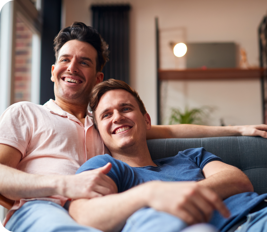 young gay couple smiling on couch