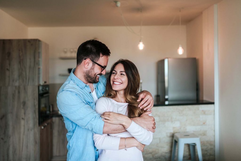 Couple smiling and embracing in their home after improving erectile dysfunction