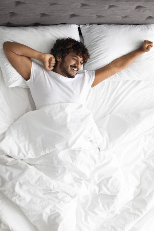 Man stretching in his bed