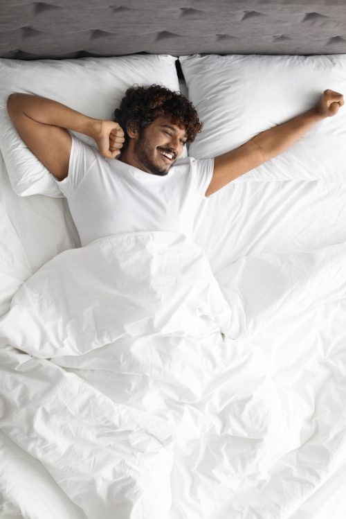 young man stretching in the morning in bed